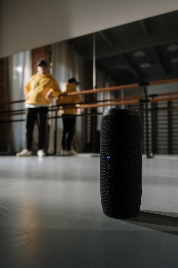 hero-gallery-03 A sleek, black wireless speaker in a modern dance studio environment with dancers.